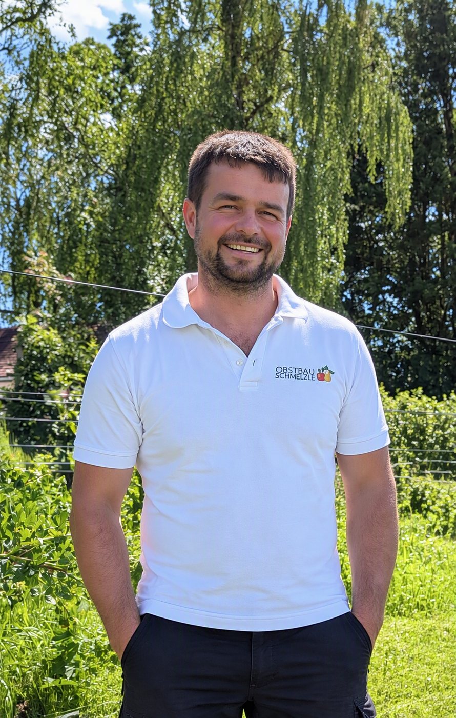 Porträt von Samuel im weißen Obstbau-Schmelzle-Polo vor grünem Garten